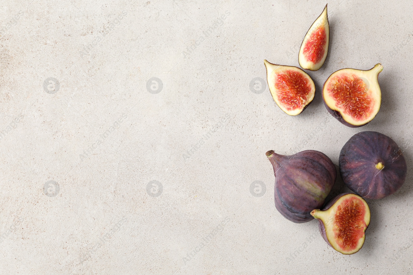 Photo of Whole and cut tasty fresh figs on grey table, flat lay. Space for text