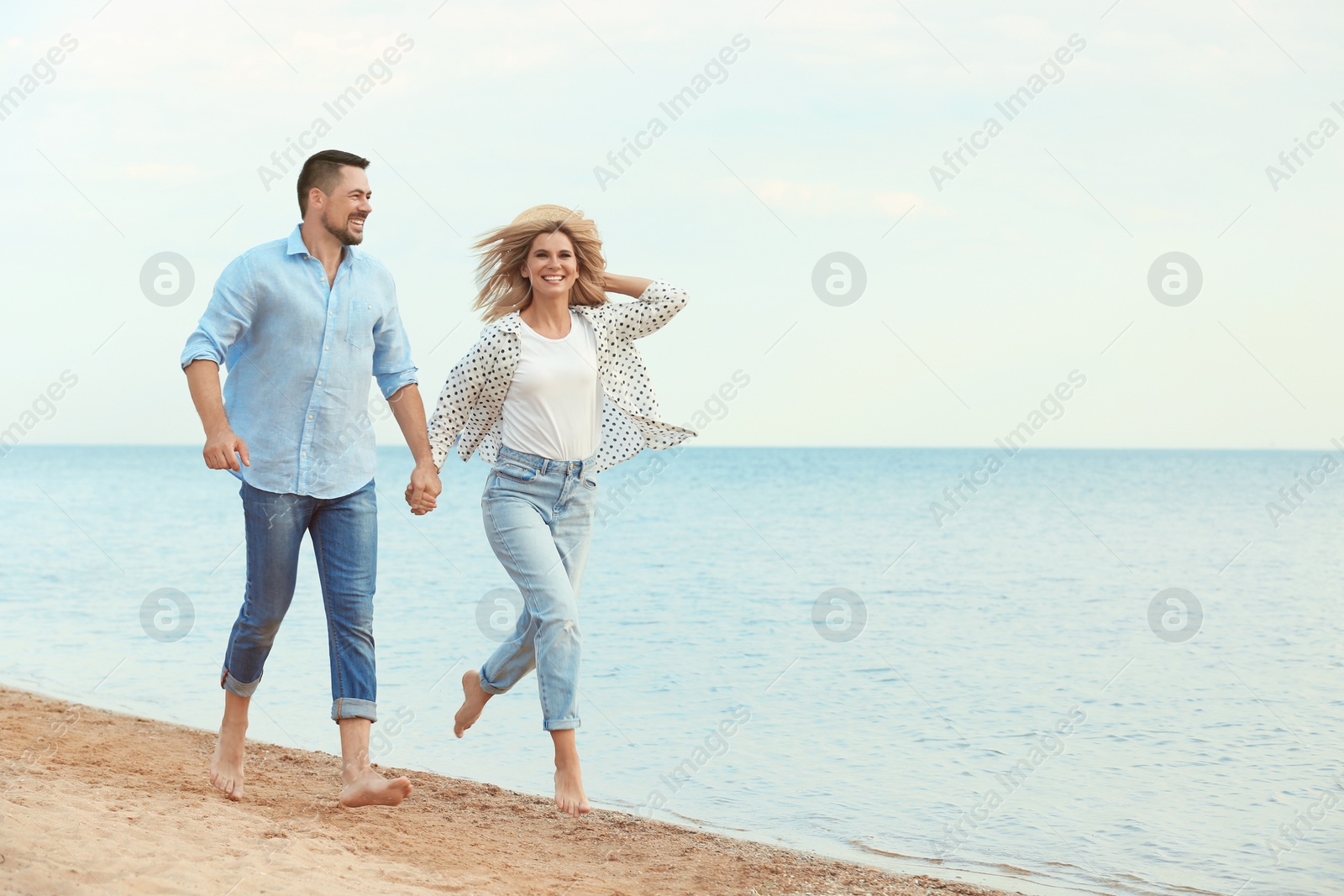 Photo of Happy romantic couple running together on beach, space for text