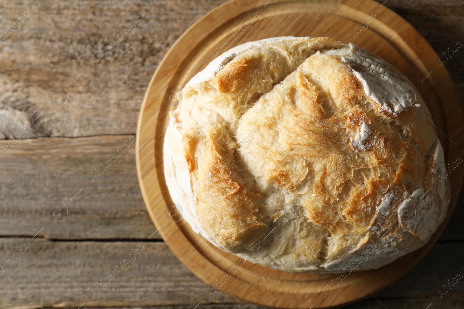 Photo of Freshly baked sourdough bread on wooden table, top view. Space for text