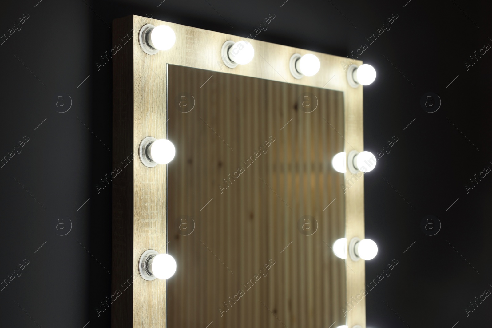 Photo of Beautiful mirror with light bulbs in makeup room, closeup