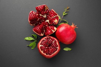 Photo of Fresh ripe pomegranates and leaves on grey background, top view