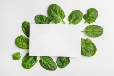 Blank card and fresh spinach leaves isolated on white, top view. Space for text