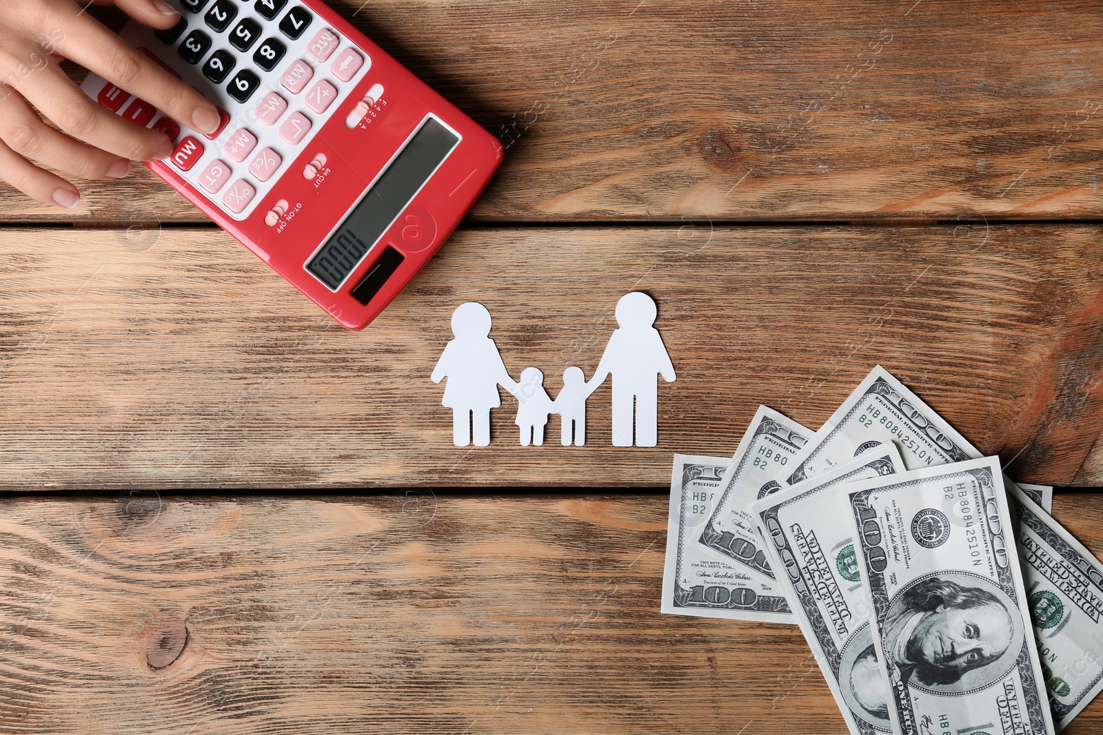 Photo of Woman using calculator and paper silhouette of family on wooden background, top view. Life insurance concept