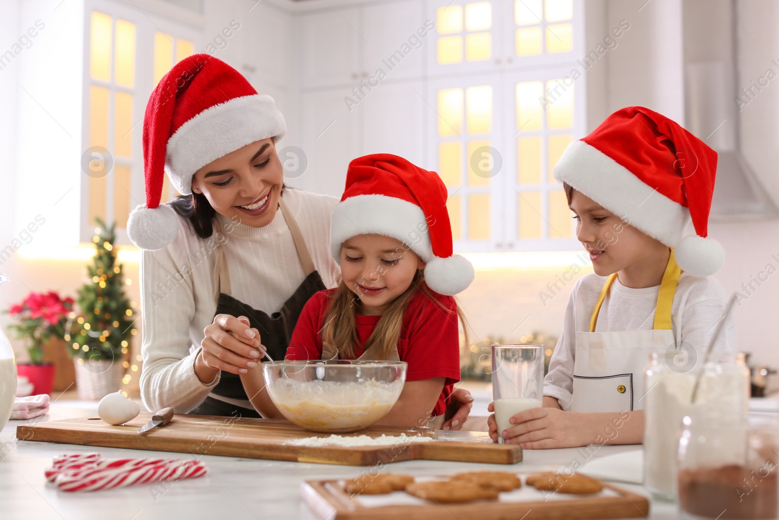 Photo of Mother with her cute little children making Christmas cookies in kitchen