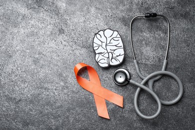 Orange ribbon, stethoscope and paper brain cutout on grey table, flat lay with space for text. Multiple sclerosis awareness