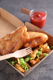 Tasty fish, chips, sauce and peas in paper box on grey table, closeup