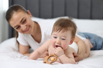 Happy mother with her baby on bed at home, selective focus
