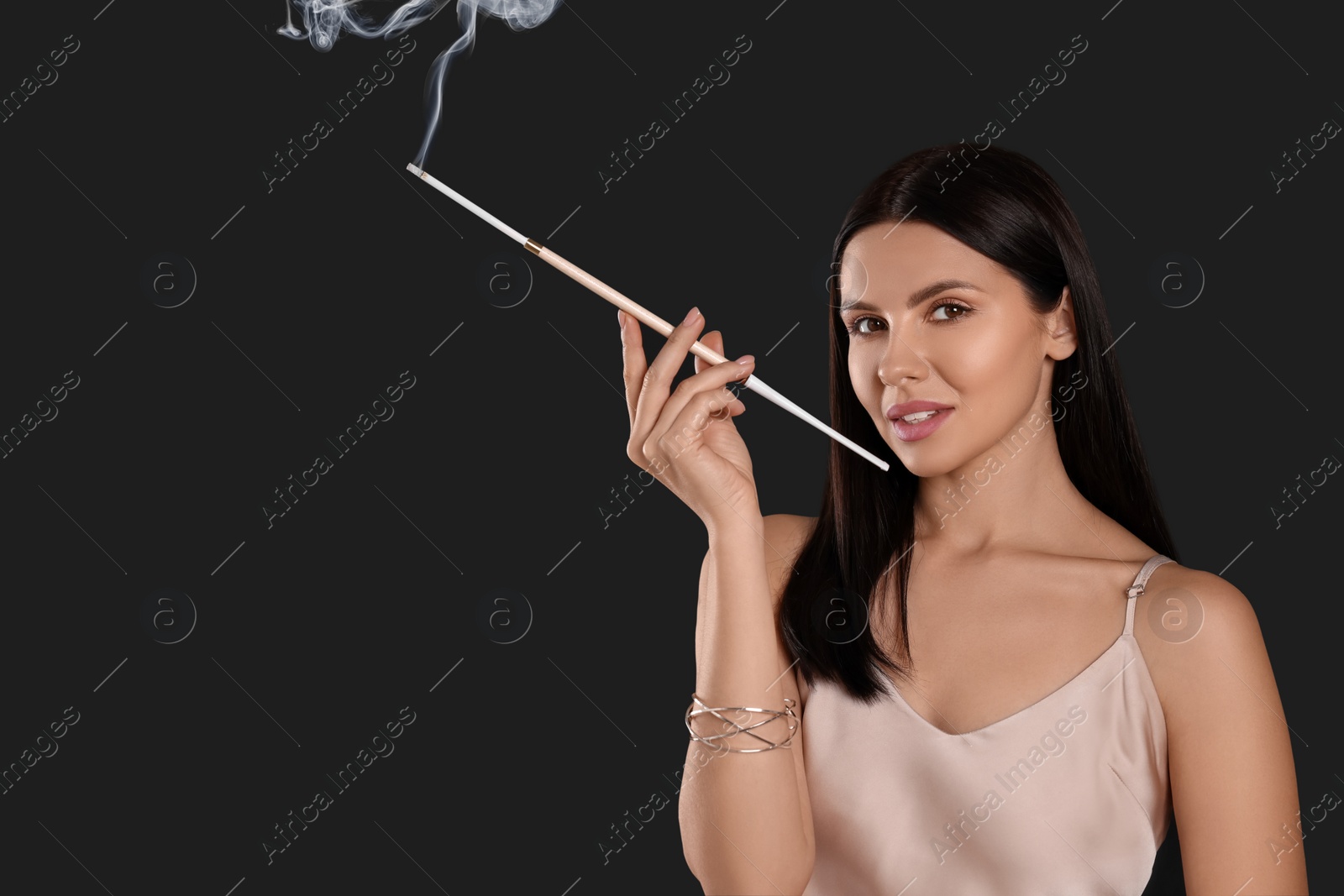 Photo of Woman using long cigarette holder for smoking on black background, space for text