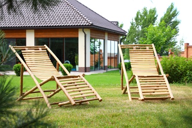 Wooden deck chairs in beautiful garden on sunny day