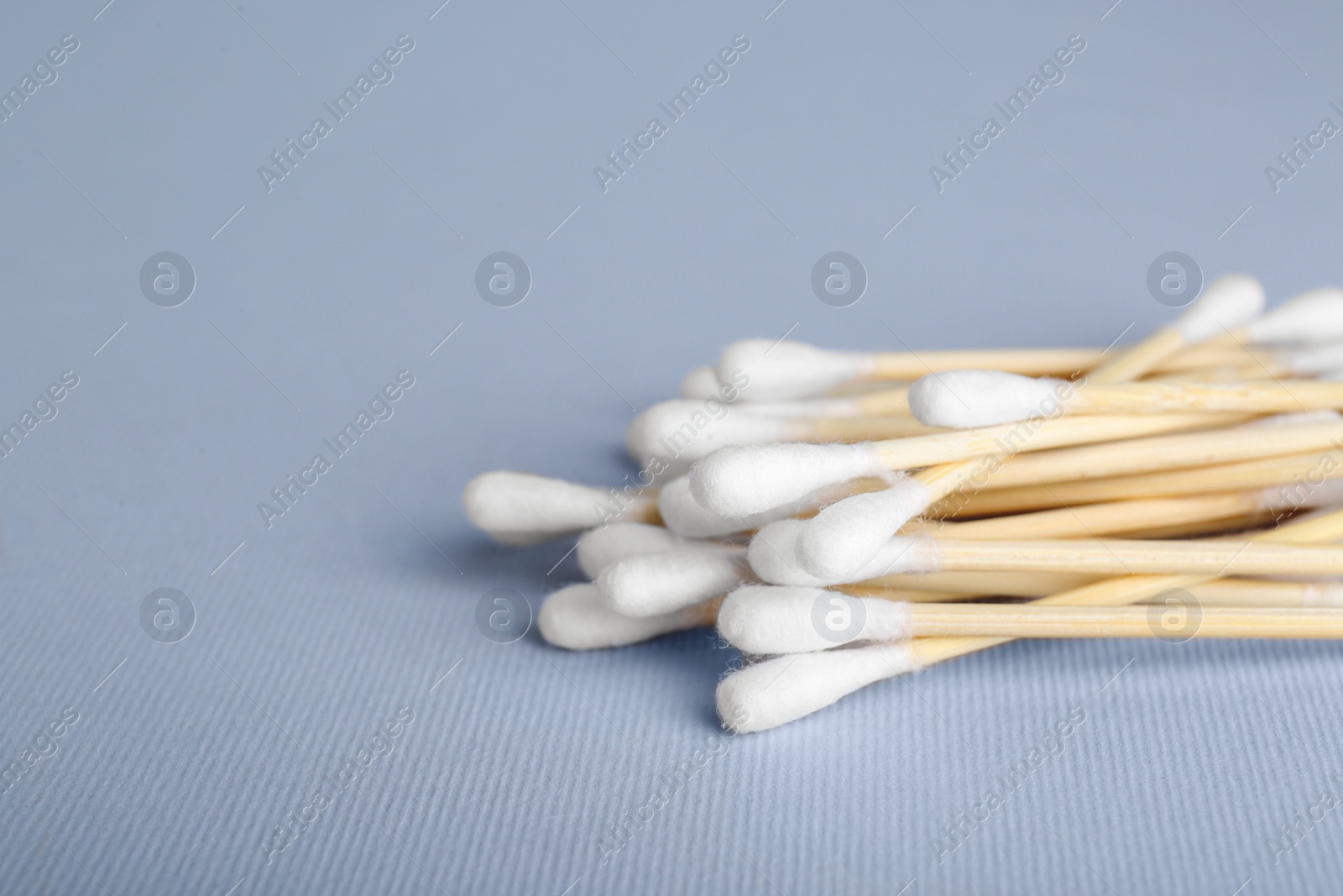 Photo of Wooden cotton buds on light grey background, closeup. Space for text