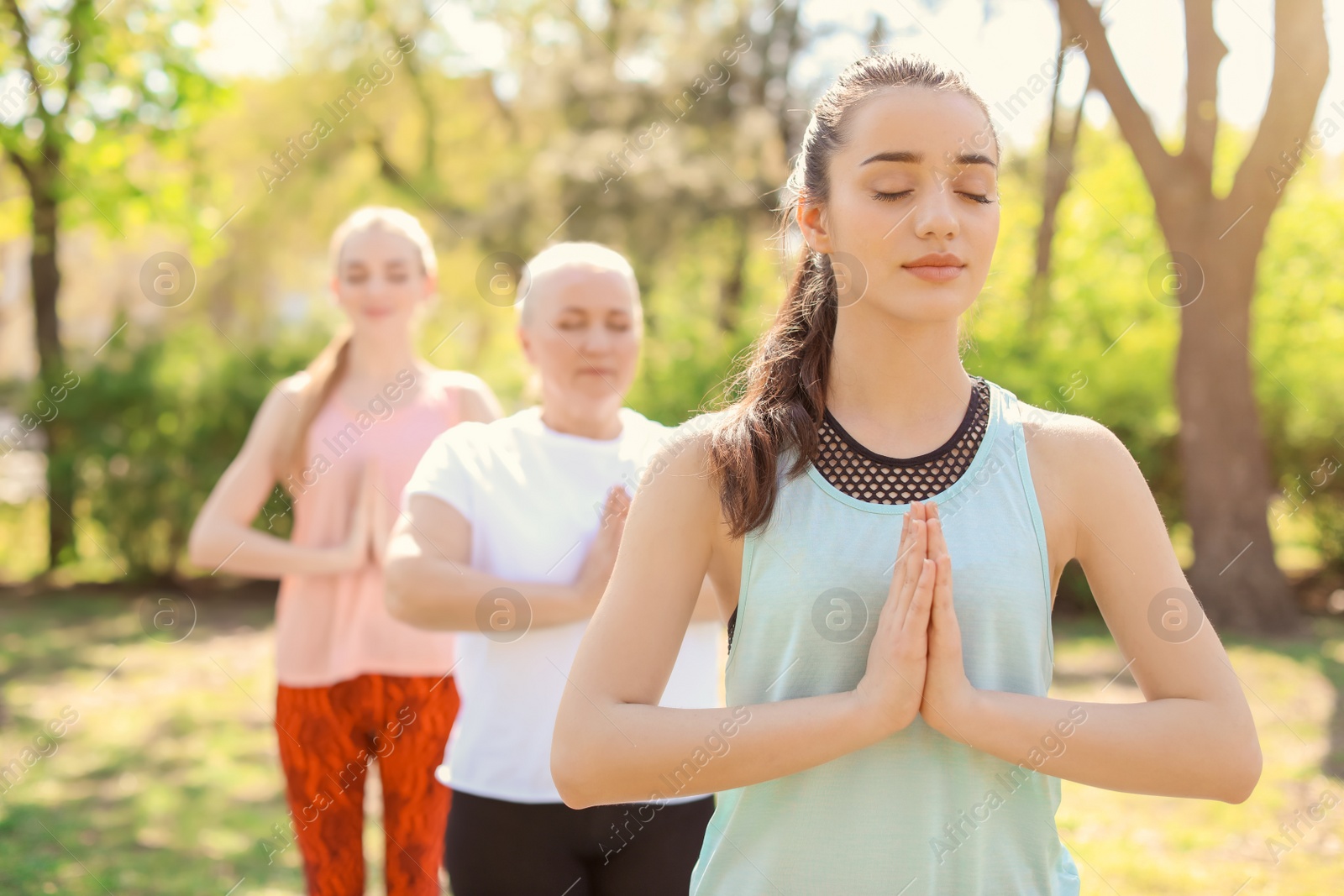 Photo of Group of women practicing yoga in park on sunny day