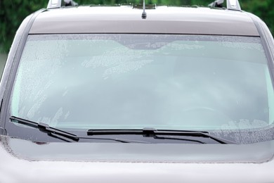 Car wipers cleaning water drops from windshield glass, closeup