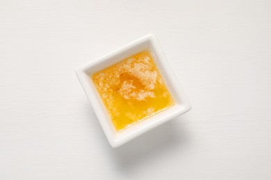 Photo of Melted butter in bowl on white wooden table, top view