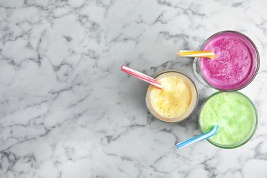 Photo of Glasses of tasty milk shakes and space for text on marble background, top view