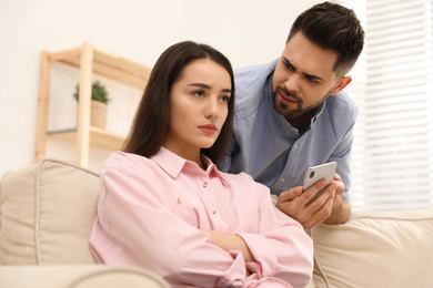 Young couple arguing about smartphone at home. Problems in relationship