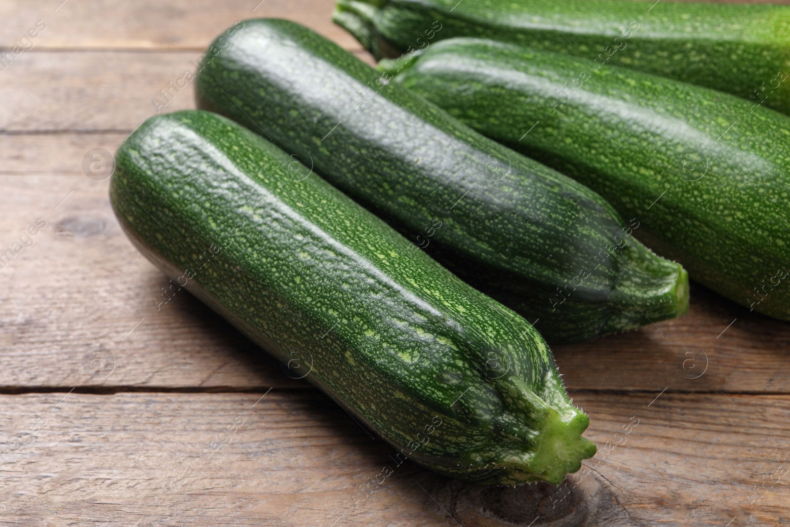 Photo of Raw ripe zucchinis on wooden table, closeup