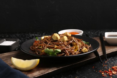 Photo of Stir-fry. Tasty noodles with vegetables and meat served on dark textured table