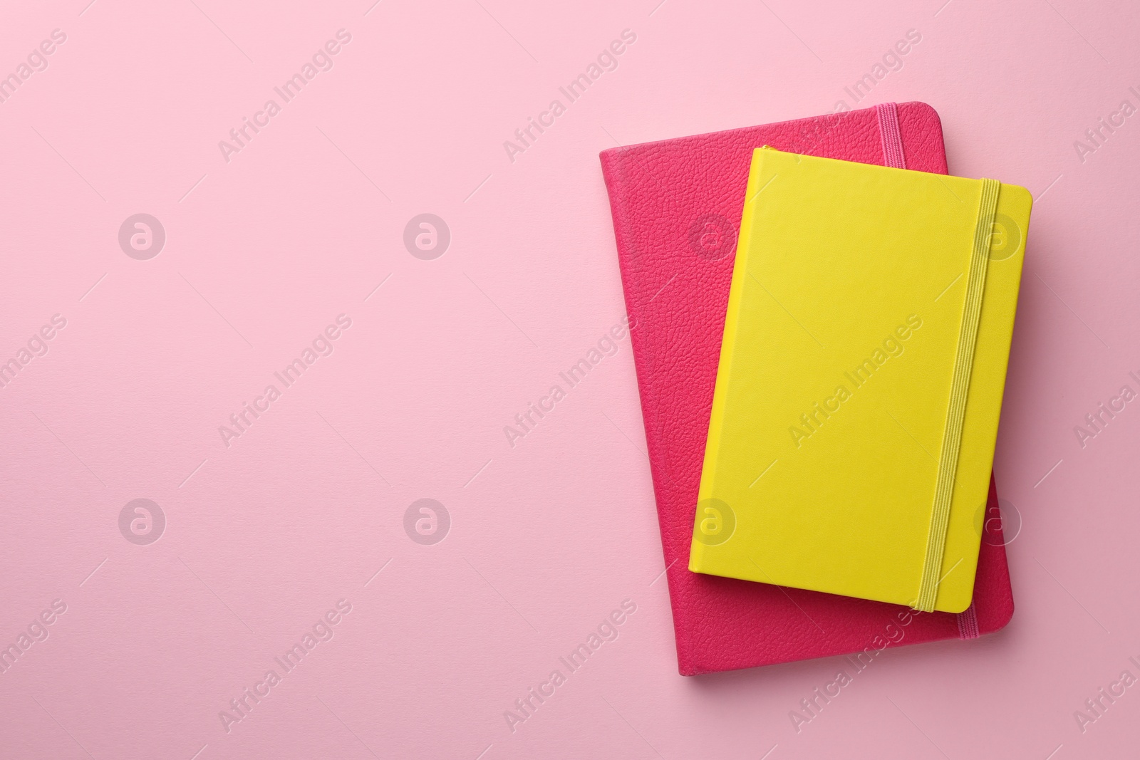 Photo of Different notebooks on light pink background, top view. Space for text