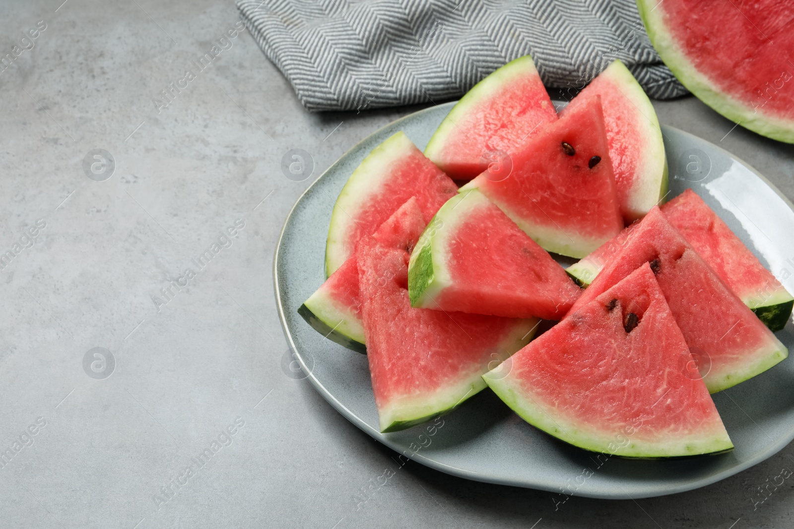 Photo of Delicious fresh watermelon slices on grey table. Space for text