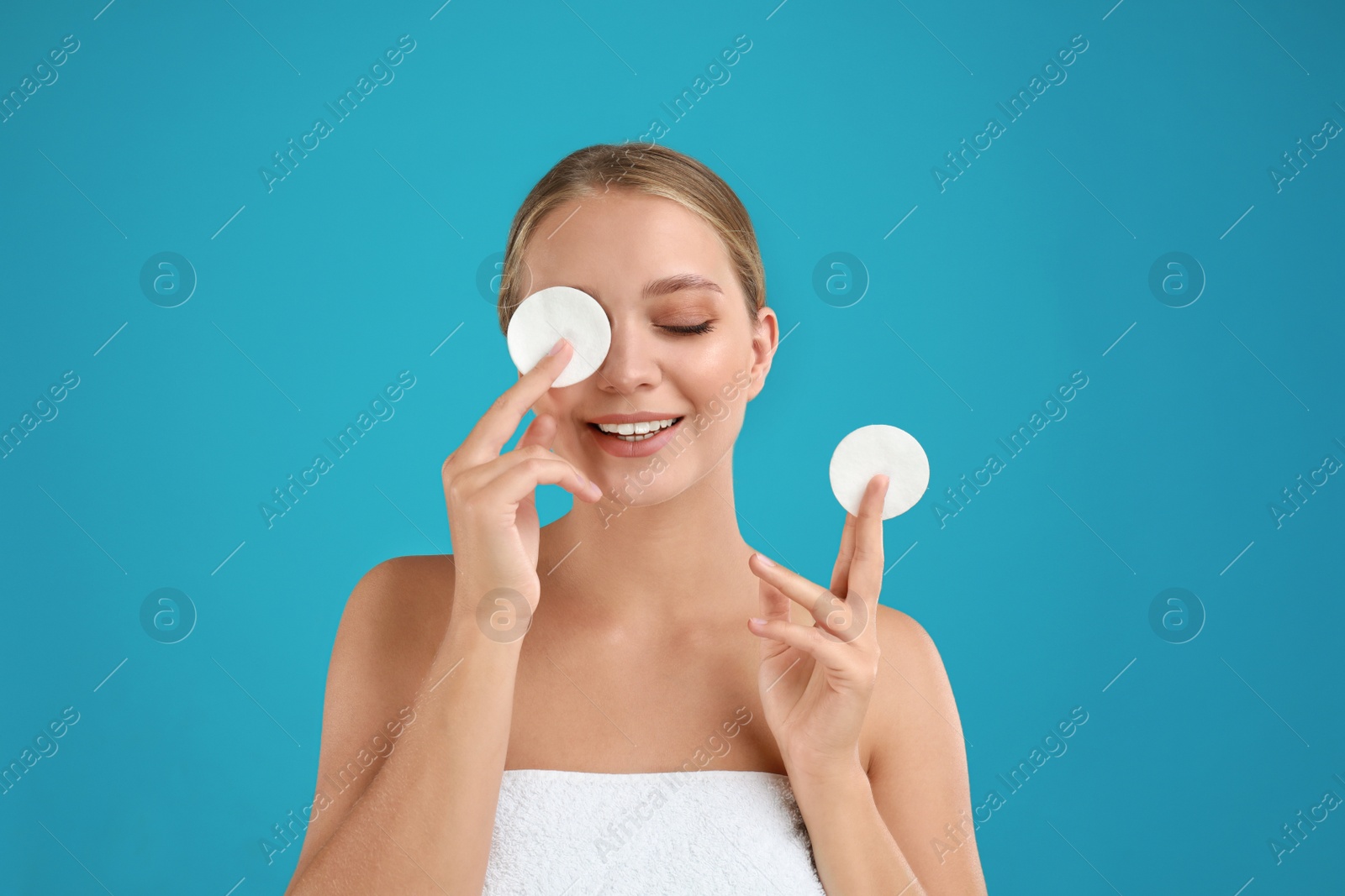 Photo of Beautiful young woman with cotton pads on turquoise background