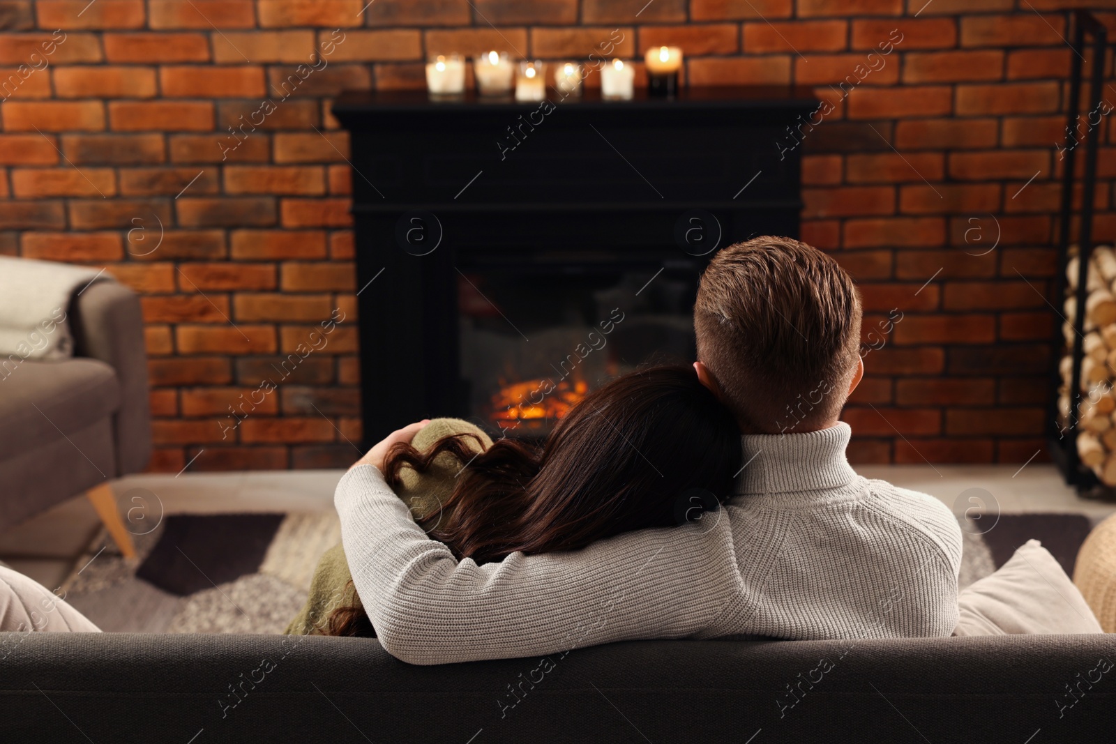 Photo of Lovely couple spending time together near fireplace at home, back view