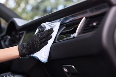 Photo of Woman wiping her modern car with rag, closeup