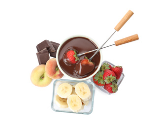 Fondue forks with strawberries in bowl of melted chocolate and other fruits on white background, top view