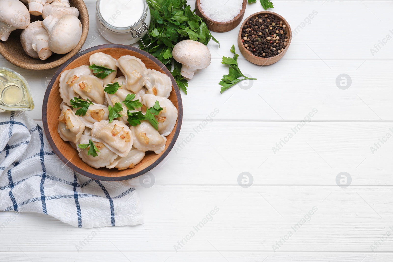 Photo of Delicious dumplings (varenyky) with potatoes, onion and parsley served on white wooden table, flat lay. Space for text