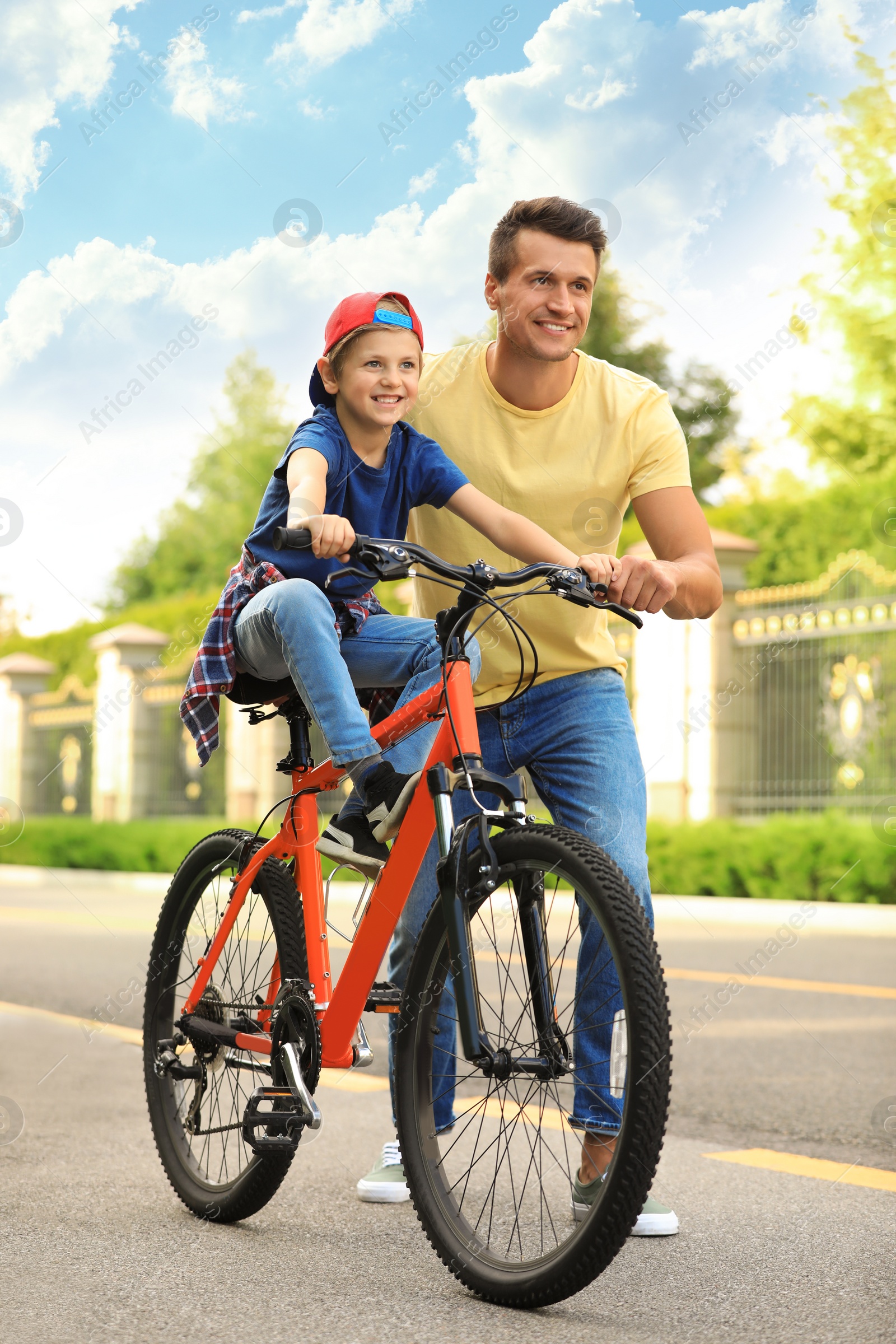 Photo of Dad teaching son to ride bicycle outdoors