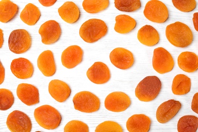 Photo of Flat lay composition with dried apricots on white wooden table. Healthy fruit