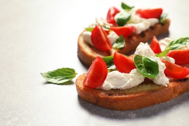 Photo of Toasted bread with tasty cream cheese and tomatoes on gray table. Space for text