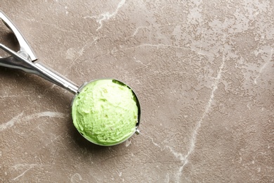 Scoop with tasty pistachio ice cream on grey table, top view. Space for text