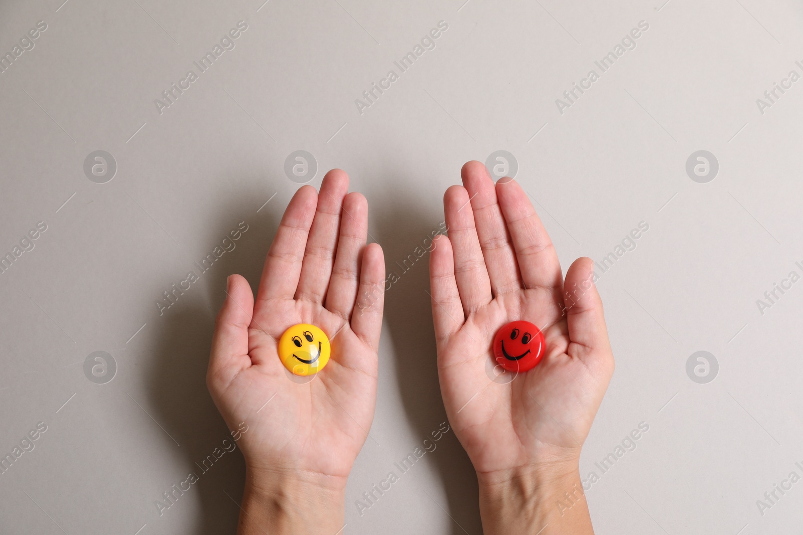 Photo of Choice concept. Woman holding magnets with happy emoticons on light background, closeup