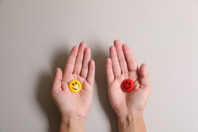 Choice concept. Woman holding magnets with happy emoticons on light background, closeup