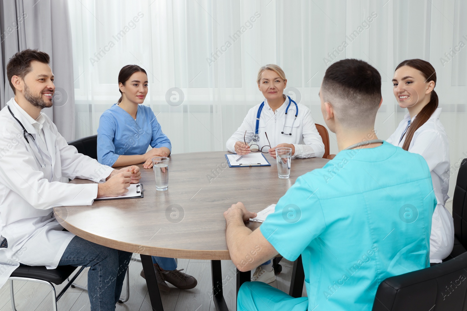 Photo of Medical conference. Team of doctors having discussion at wooden table in clinic