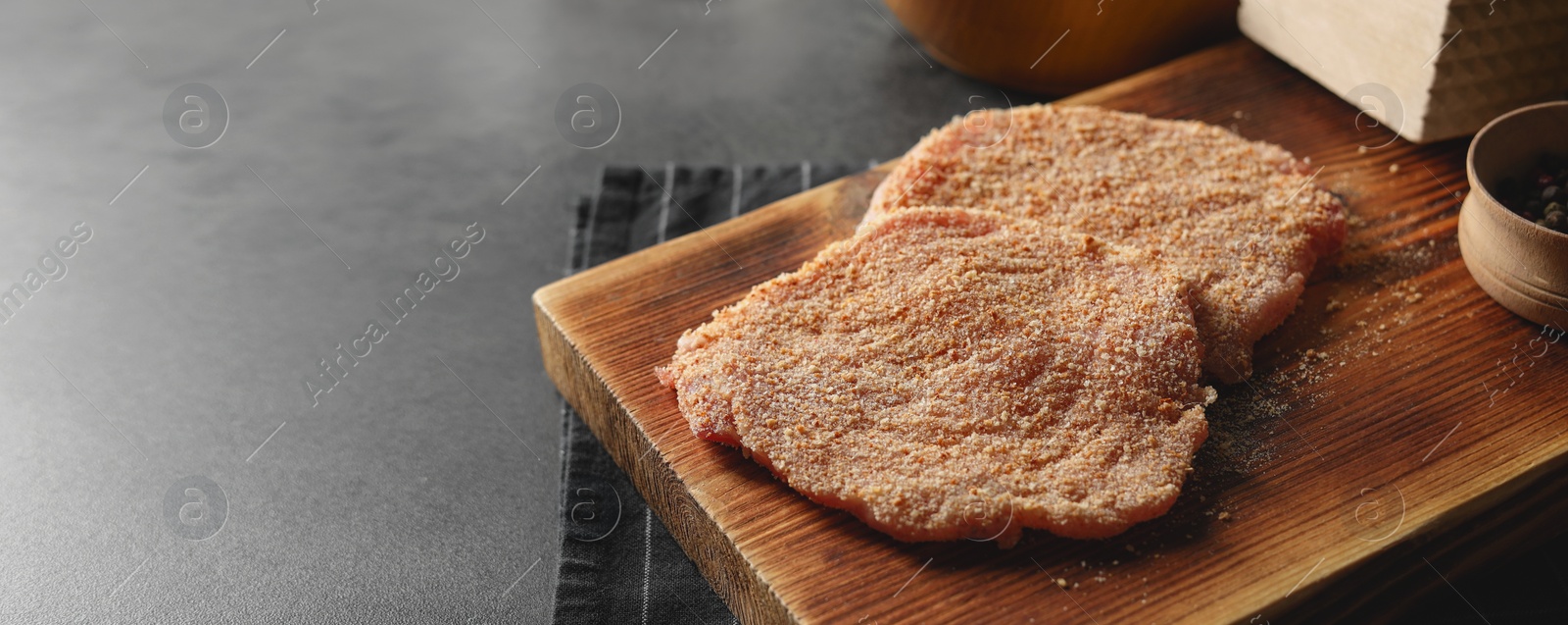 Image of Cooking schnitzel. Board with raw breaded pork slices on grey table, banner design