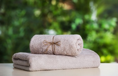 Photo of Beige soft towels on white table outdoors, closeup. Space for text