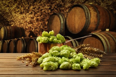 Fresh hops and wheat spikes on wooden table in beer cellar