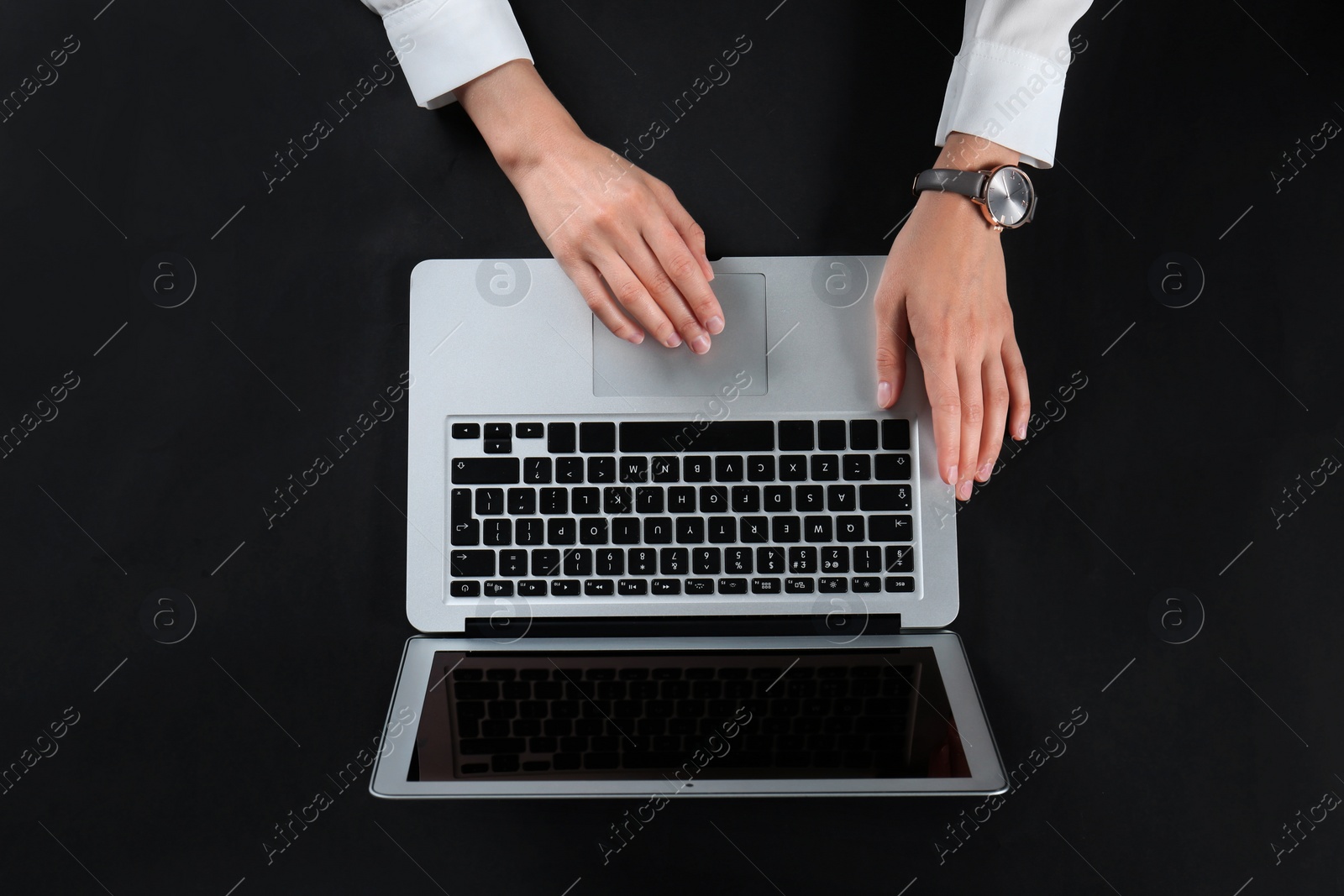Photo of Young woman using laptop on black background, top view