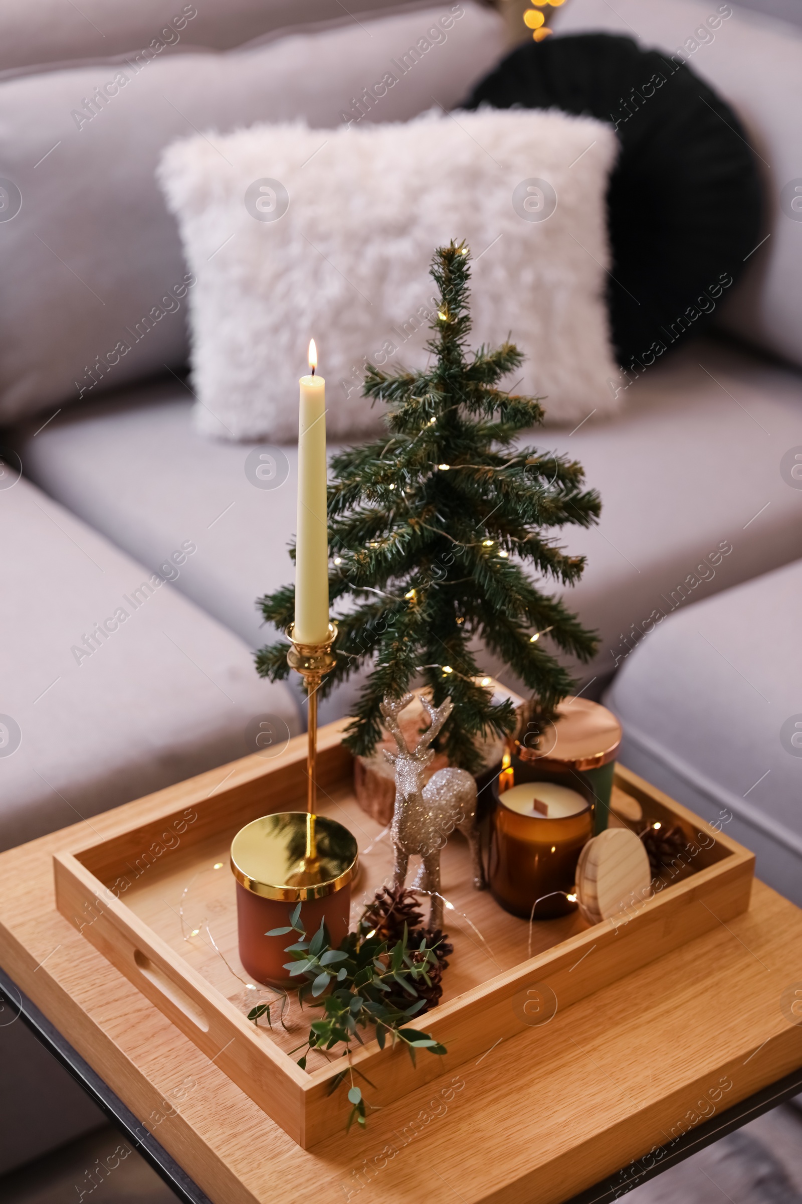 Photo of Composition with decorative Christmas tree and reindeer on wooden tray near sofa