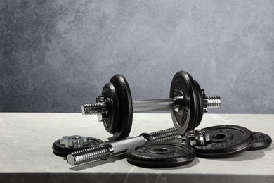 Photo of Barbell and parts of one on light table against grey background. Space for text