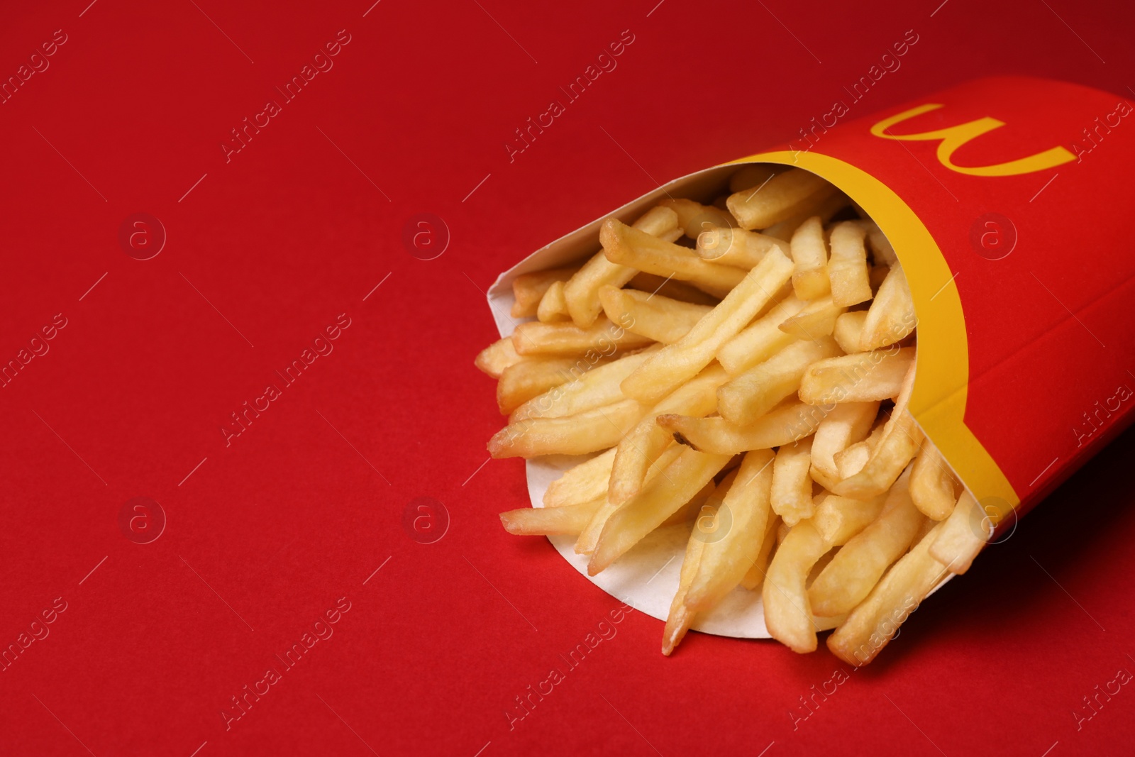 Photo of MYKOLAIV, UKRAINE - AUGUST 12, 2021: Big portion of McDonald's French fries on red background, closeup. Space for text