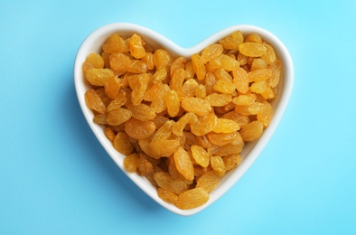 Photo of Bowl with raisins on color background, top view. Dried fruit as healthy snack