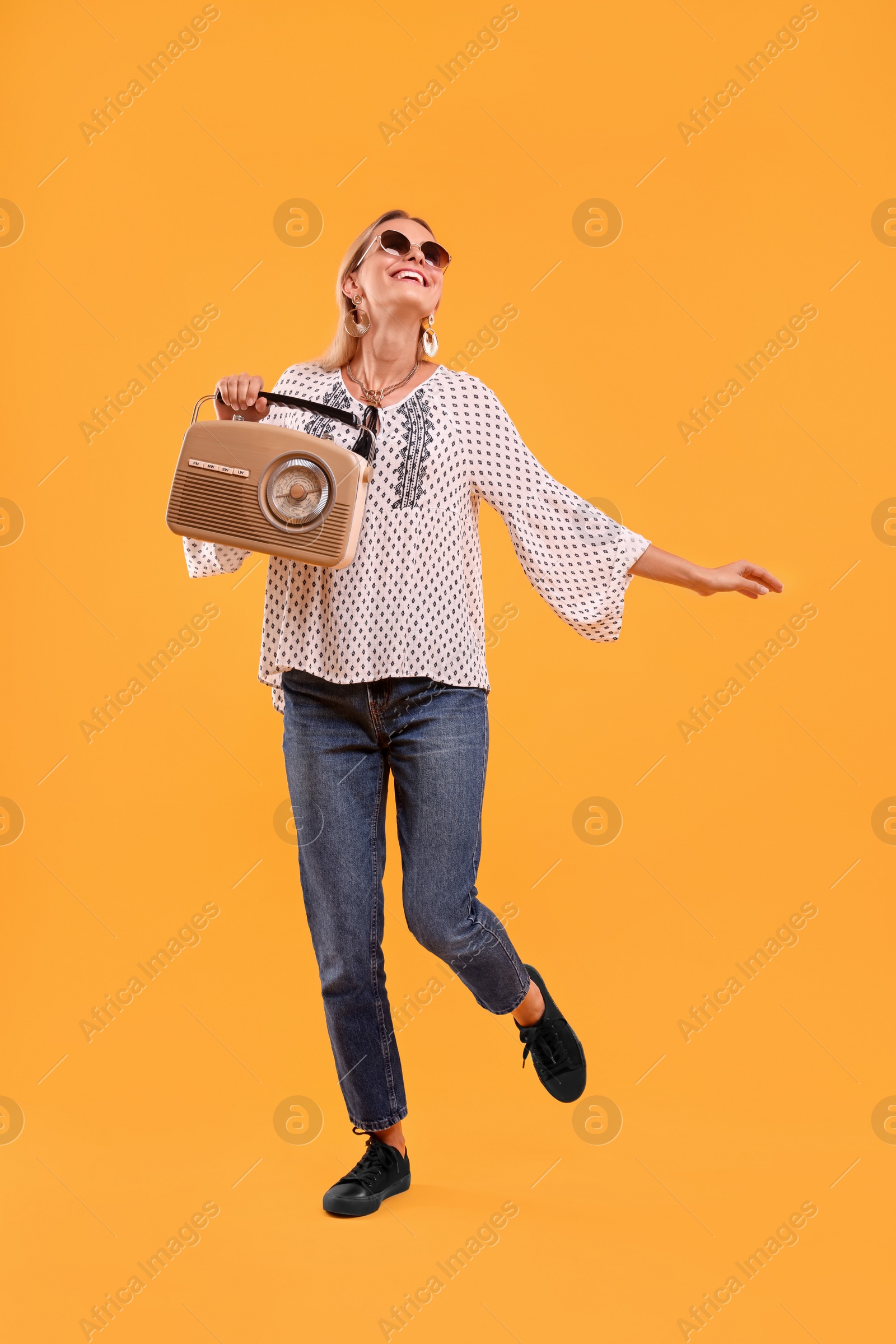 Photo of Portrait of happy hippie woman with retro radio receiver on yellow background