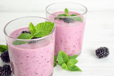 Photo of Delicious blackberry smoothie in glasses on white table, closeup