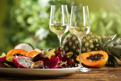 Delicious exotic fruits and wine on wooden table