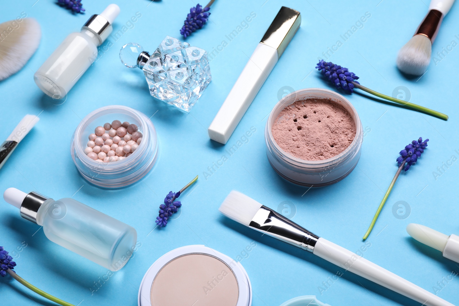 Photo of Composition with different makeup products and beautiful spring flowers on light blue background