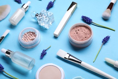 Composition with different makeup products and beautiful spring flowers on light blue background