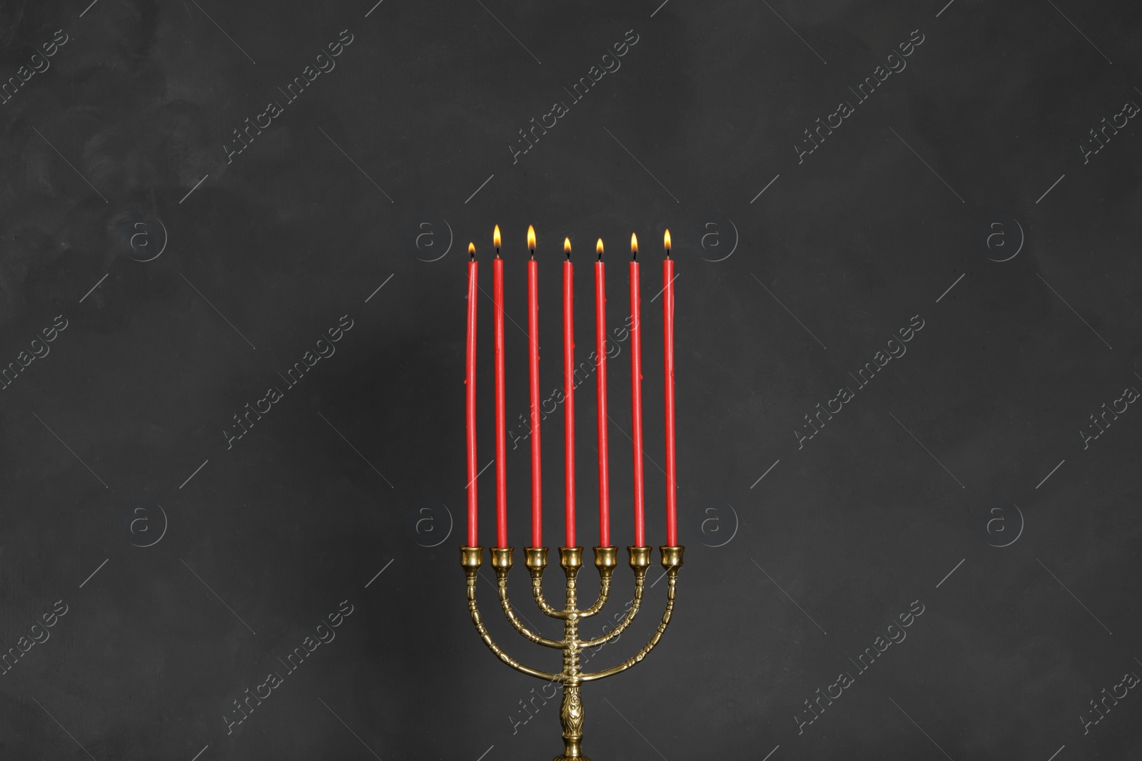 Photo of Golden menorah with burning candles on black background