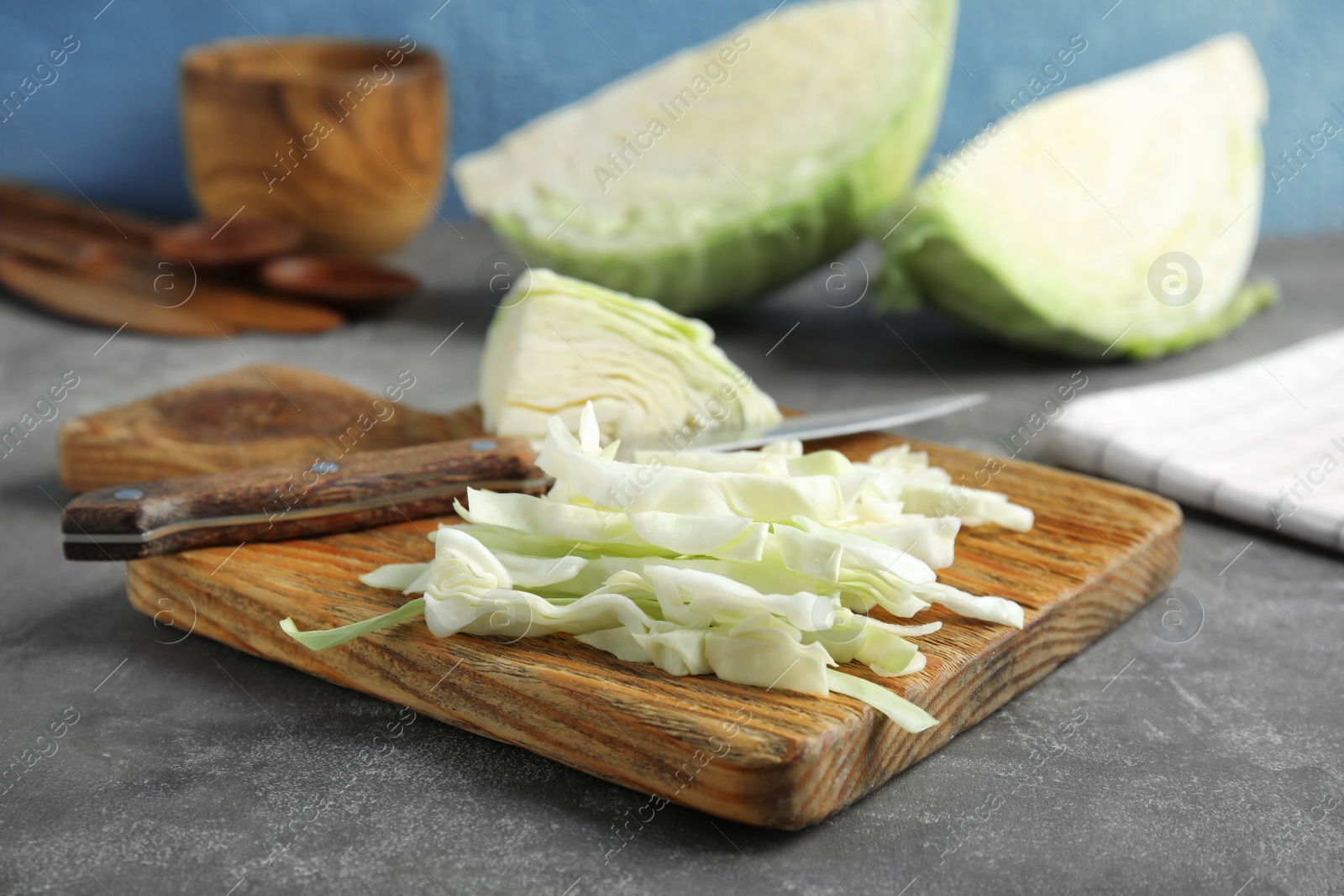 Photo of Cutting board with chopped and sliced cabbage on table